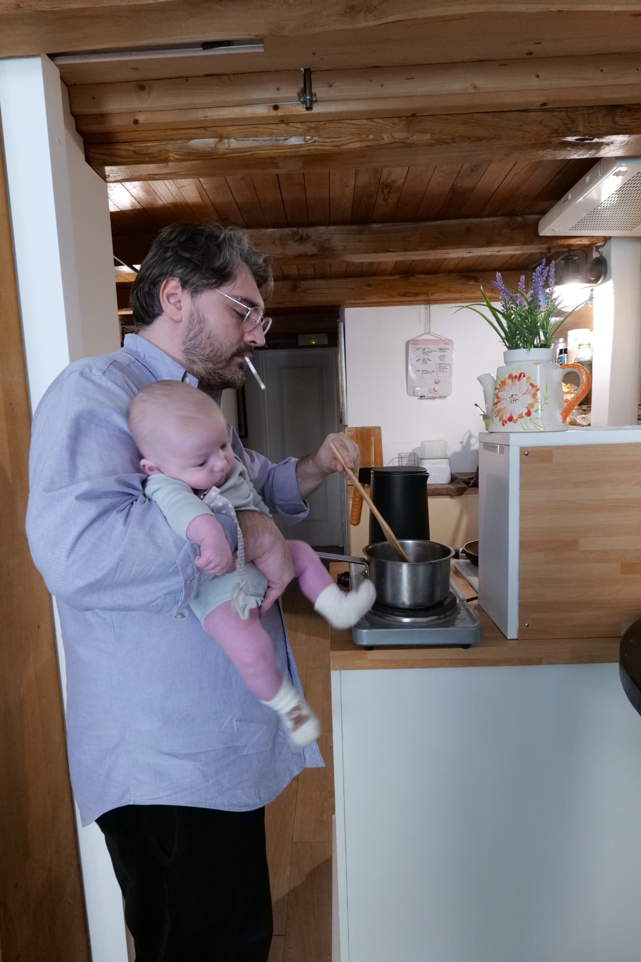 Original reference photograph: a father cooking at the stove while holding his baby