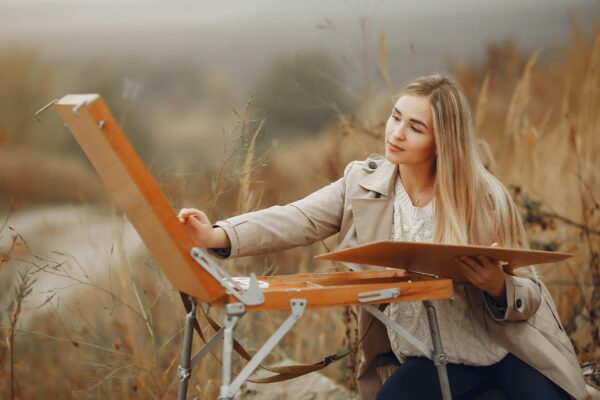 Young woman painting outdoors in an autumn setting, capturing creativity and tranquility.