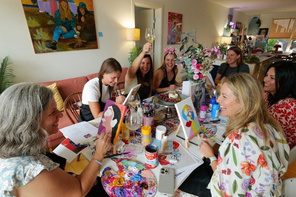 Happy participants painting on canvas and enjoying wine at a Painting and Wine event in Copenhagen.